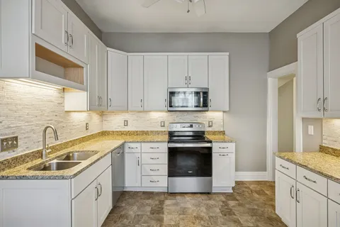 a kitchen with stainless steel appliances granite countertop a sink stove and cabinets