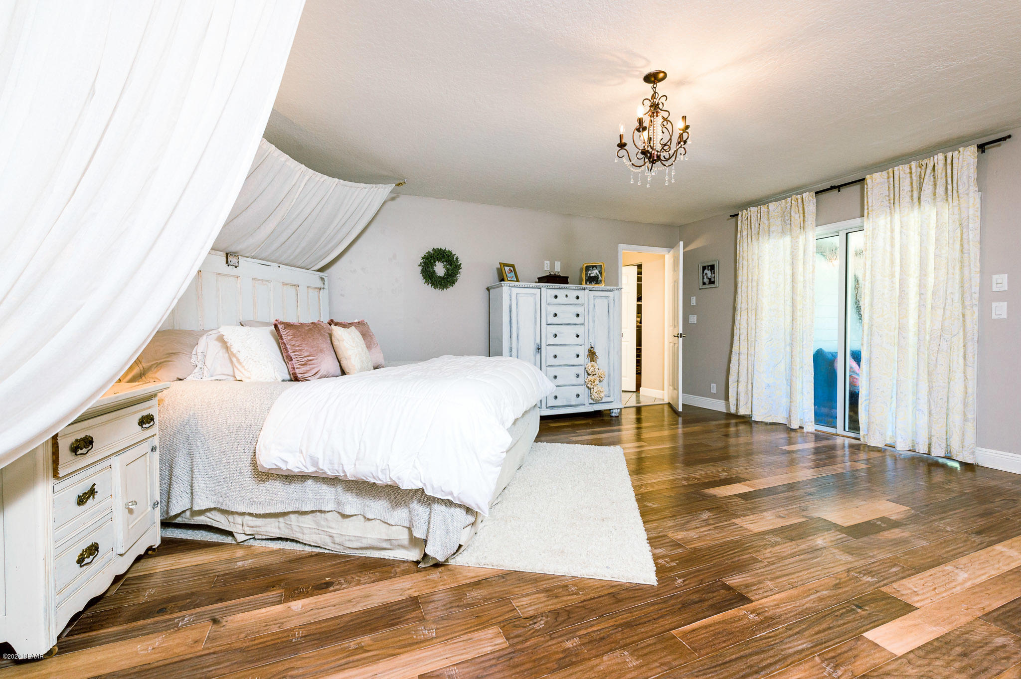 35 Neptune Avenue Ormond Beach, FL 32176 - Photo 33 of 58 a spacious bedroom with a bed and a chandelier