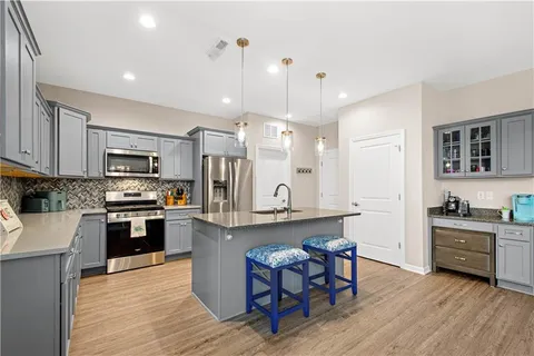 a kitchen with stainless steel appliances granite countertop a refrigerator a stove top oven a sink dishwasher and white cabinets with wooden floor