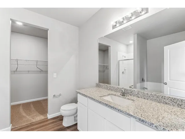a bathroom with a granite countertop sink toilet a large mirror a vanity and shower