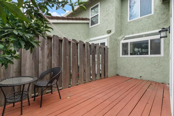 a backyard of a house with table and chairs potted plants and wooden fence