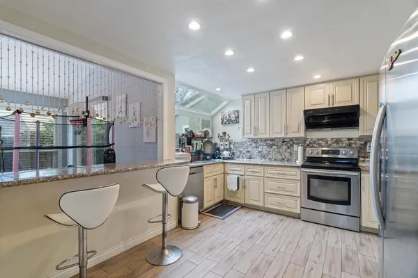 a kitchen with stainless steel appliances granite countertop a stove a sink and a microwave