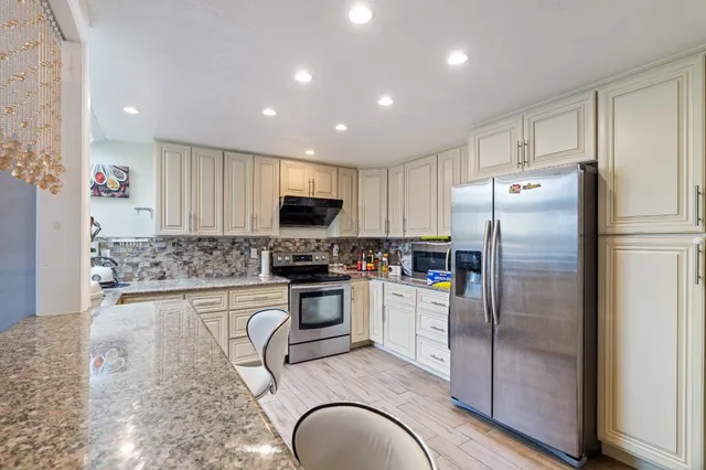 a kitchen with granite countertop a refrigerator and a stove top oven