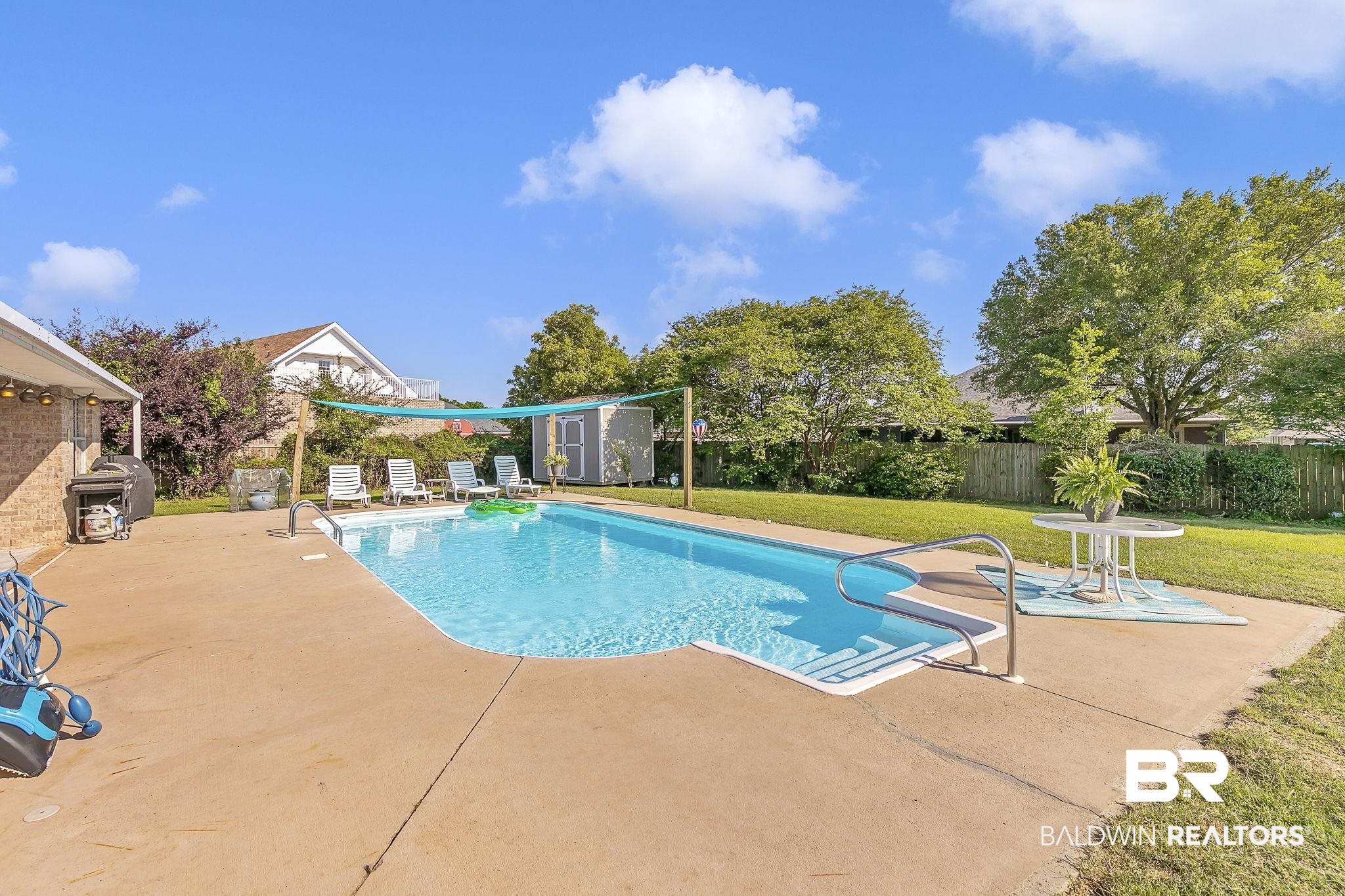 16358 Tempest Drive Foley, AL 36535 - Photo 38 of 46 View of swimming pool featuring a fenced backyard, a storage shed, a patio area, an outdoor structure, and a lawn