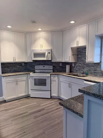 a kitchen with granite countertop wooden cabinets and white appliances