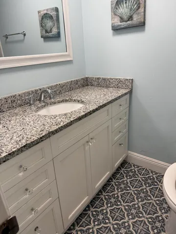 a bathroom with a granite countertop sink and a mirror