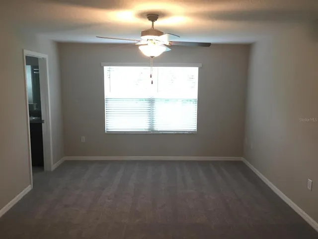 an empty room with a window and a chandelier fan