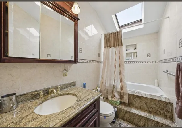 a bathroom with a granite countertop sink toilet a mirror and bathtub