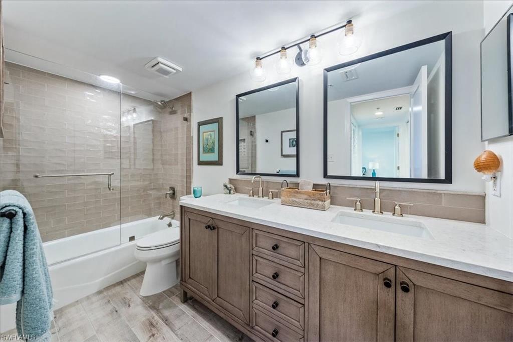 6573 Marissa Loop, Unit 1002 Naples, FL 34108 - Photo 13 of 24 a bathroom with a double vanity sink toilet mirror and bathtub
