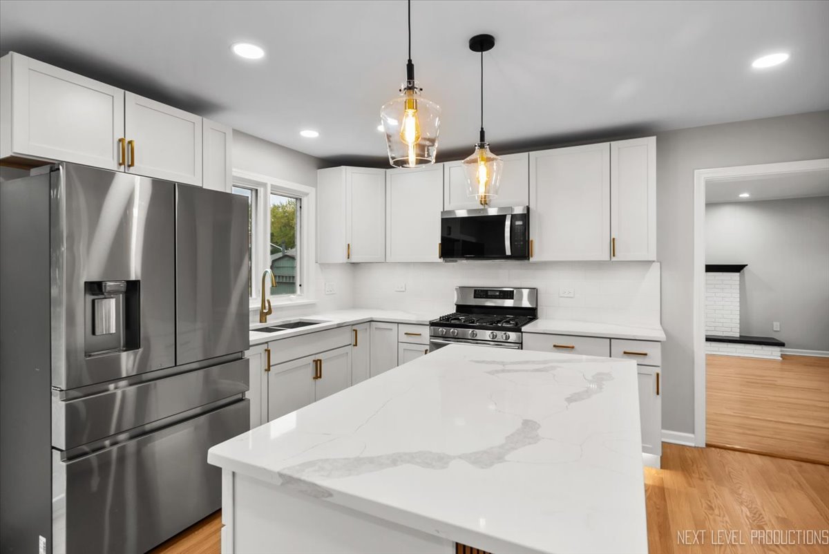 27 South Canterbury Road Aurora, IL 60506 - Photo 4 of 39 a kitchen with granite countertop a refrigerator oven a sink and white cabinets