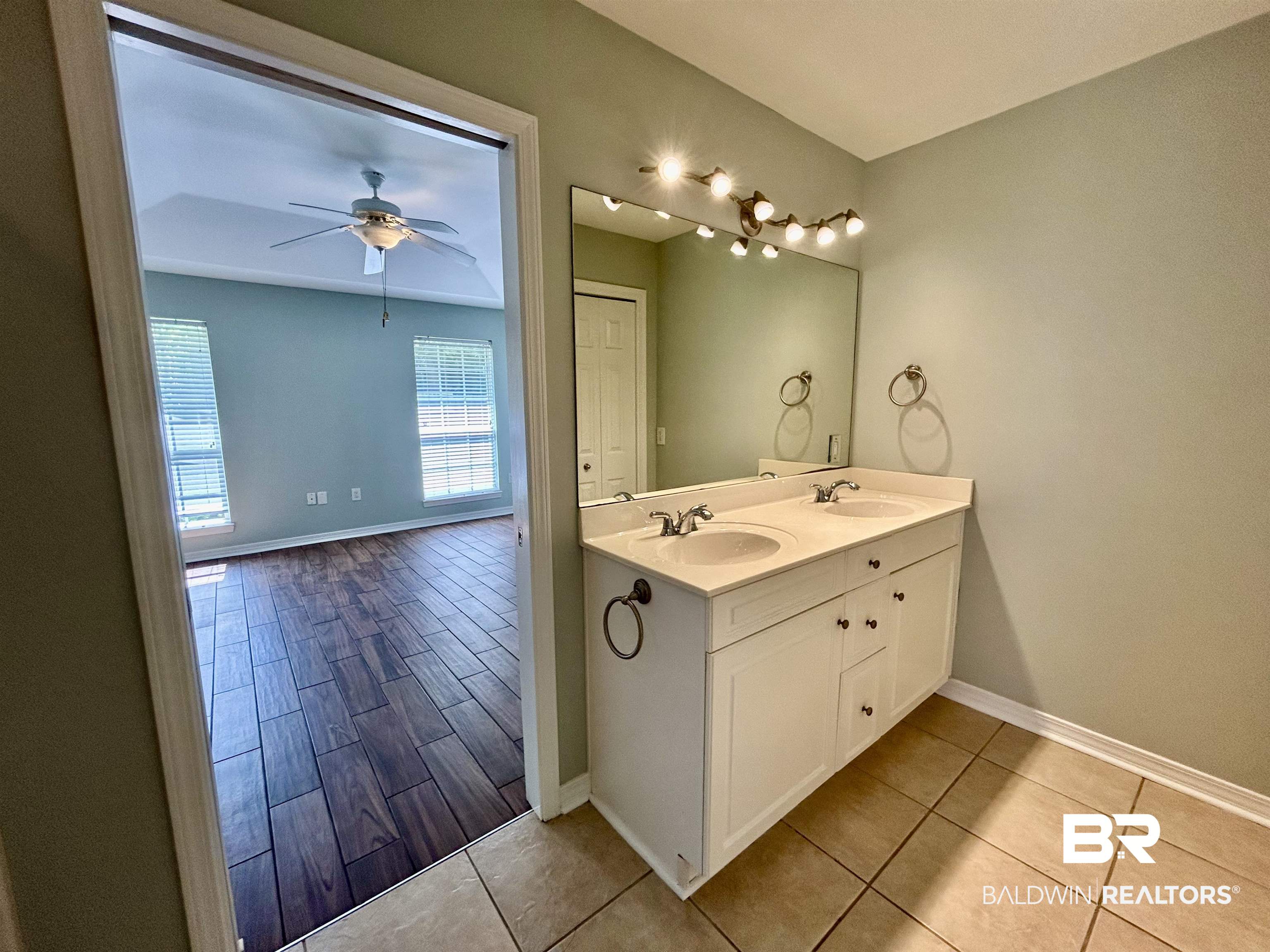 7198 Raintree Lane Gulf Shores, AL 36542 - Photo 17 of 33 Dual vanity with integrated sinks and white cabinetry, complemented by a large mirror and multi-bulb lighting
