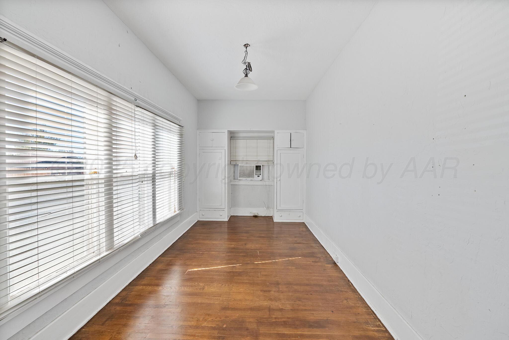 4124 Crockett Street Amarillo, TX 79110 - Photo 11 of 25 a view of an empty room with wooden floor and a window