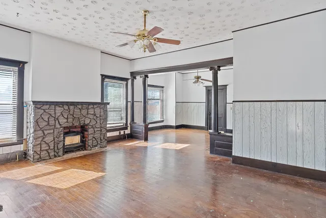 an empty room with windows fireplace and wooden floor