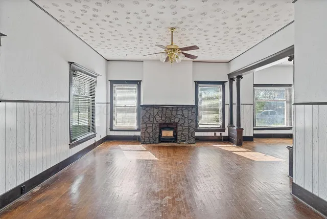 a view of an empty room with wooden floor fireplace and a window