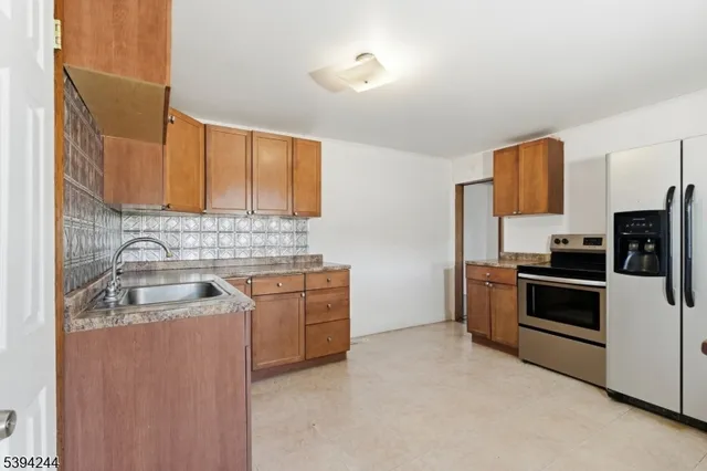 a kitchen with stainless steel appliances granite countertop a sink stove refrigerator and microwave