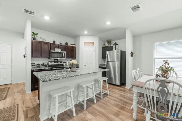 a kitchen with stainless steel appliances granite countertop a refrigerator and a stove top oven