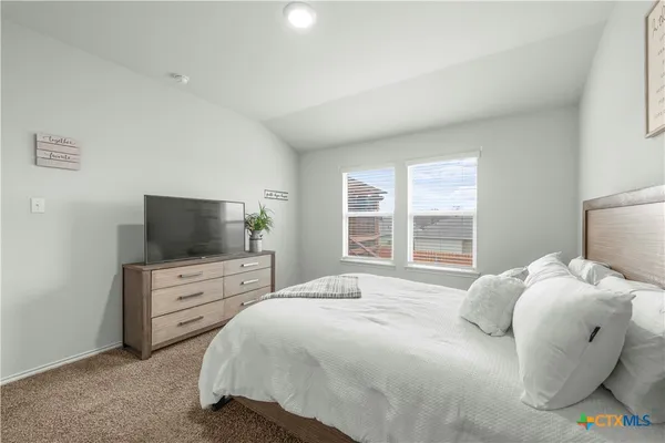 a bedroom with a large bed and flat tv screen on a dresser