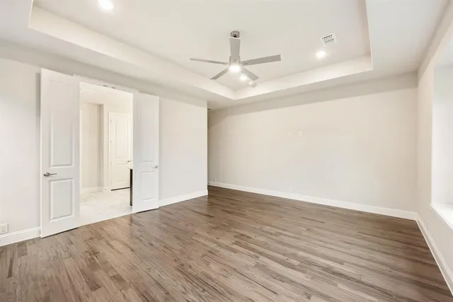 an empty room with wooden floor ceiling fan and windows