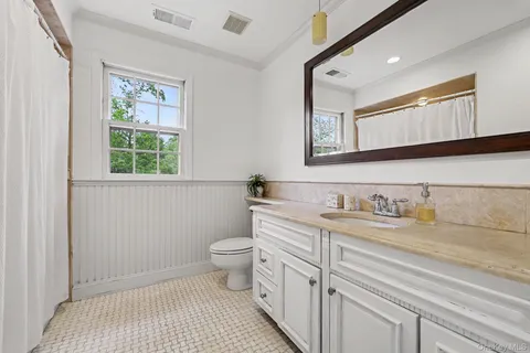 a bathroom with a granite countertop sink a toilet and a mirror