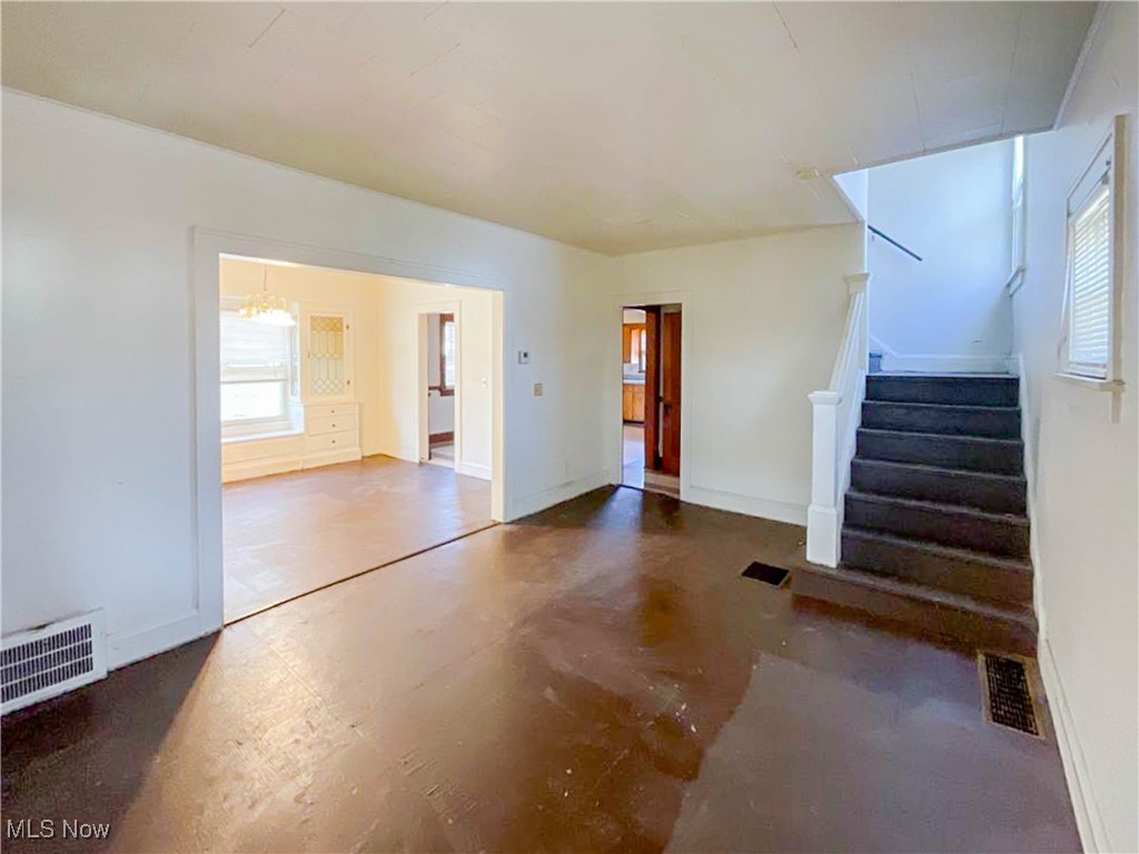 14703 Granger Road Maple Heights, OH 44137 - Photo 8 of 35 Unfurnished living room with stairway, visible vents, baseboards, and an inviting chandelier