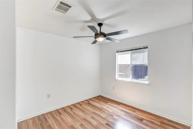an empty room with a window and a fan
