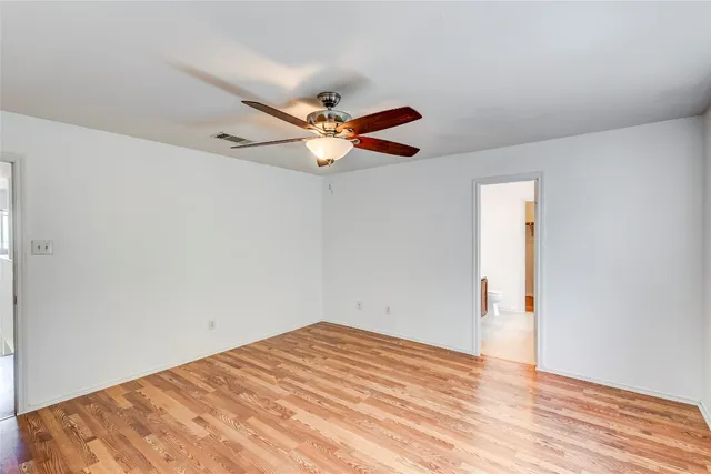 an empty room with wooden floor and ceiling fan