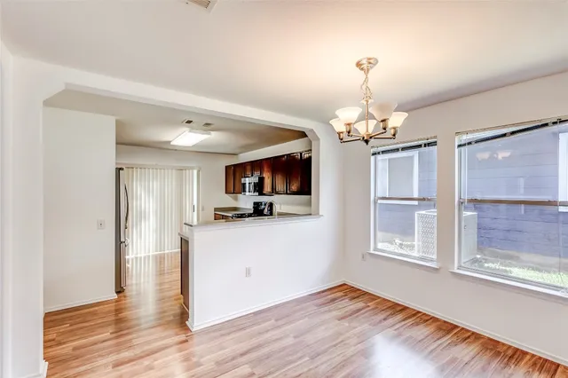 a view of a hallway with wooden floor and a kitchen