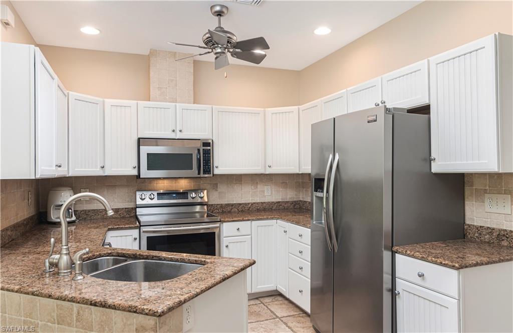 4049 Skyway Drive Naples, FL 34112 - Photo 10 of 31 a kitchen with stainless steel appliances granite countertop a sink a stove a refrigerator a center island and cabinets