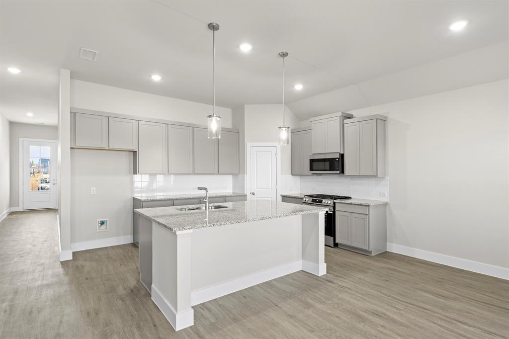 2372 Bell Way Forney, TX 75126 - Photo 14 of 39 a kitchen with stainless steel appliances granite countertop a stove top oven a refrigerator a sink and white cabinets with wooden floor