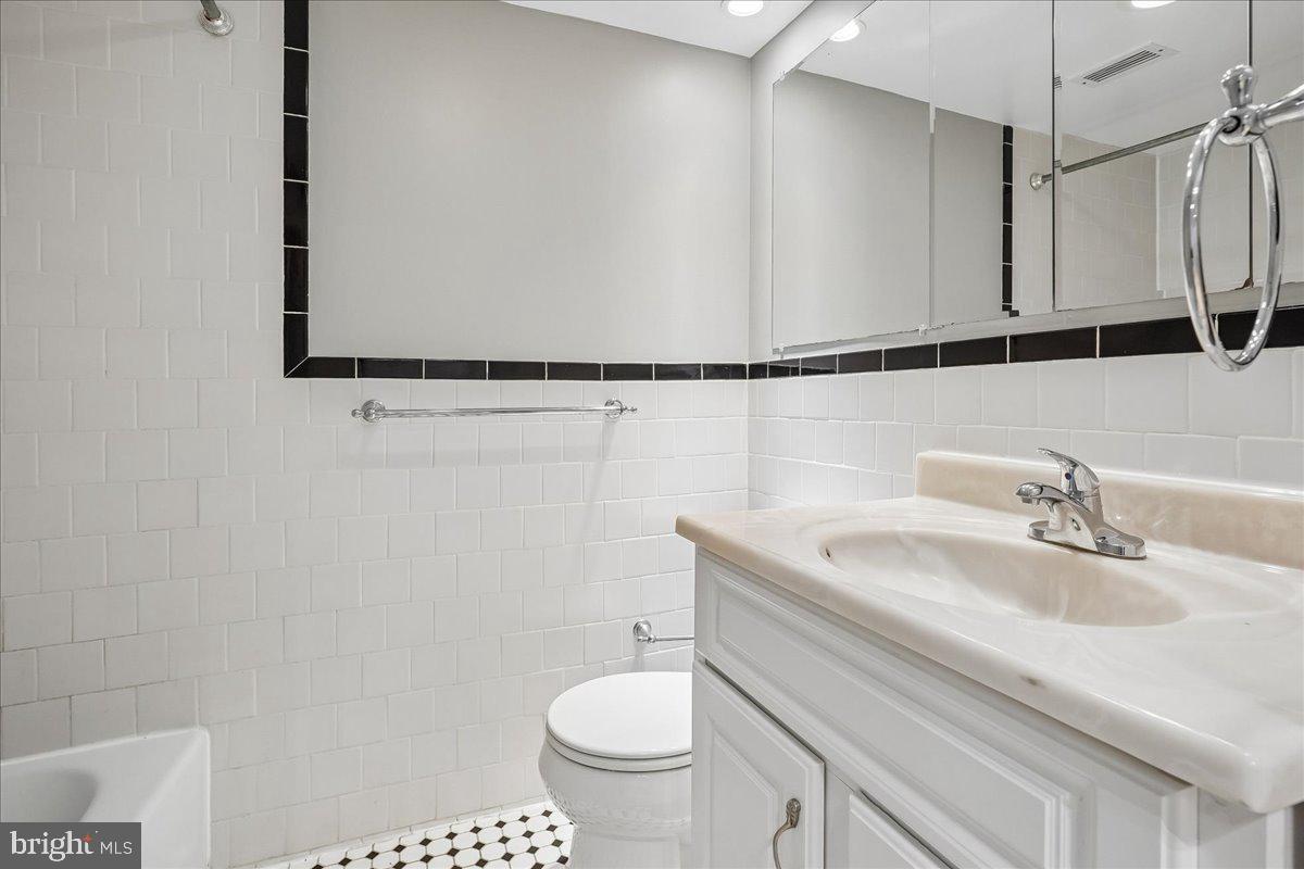 1245 4th Street Southwest, Unit E409 Washington, DC 20024 - Photo 15 of 21 a bathroom with a granite countertop sink a toilet and a mirror