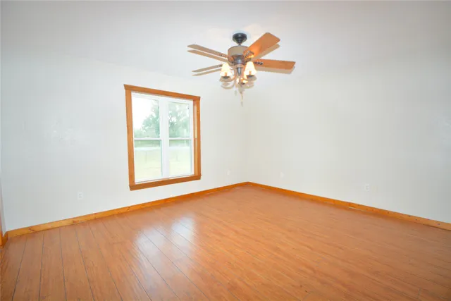 a view of empty room with wooden floor and fan