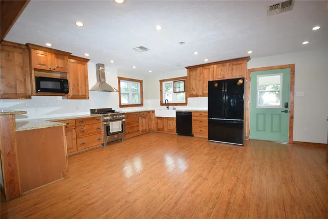 a kitchen with stainless steel appliances wooden floors and refrigerator