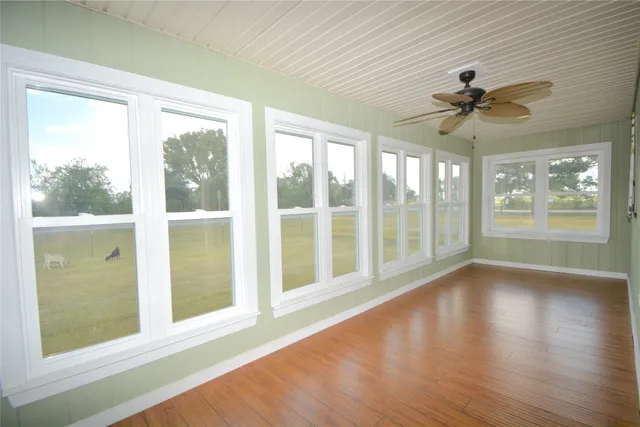 a view of an empty room with a window and wooden floor
