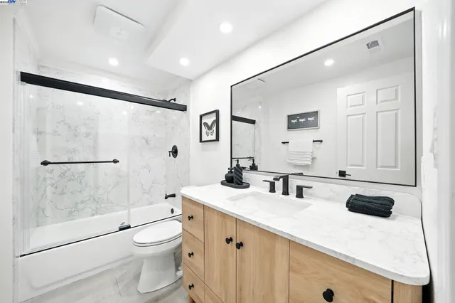 a bathroom with a sink a toilet a mirror and shower