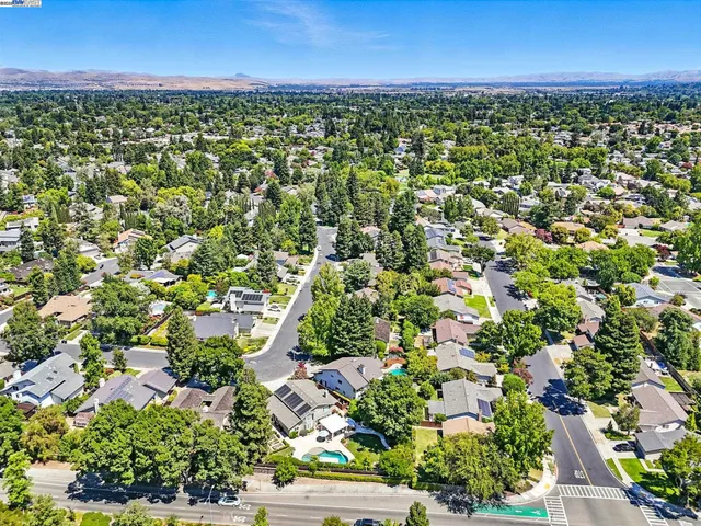 an aerial view of residential houses with outdoor space and trees