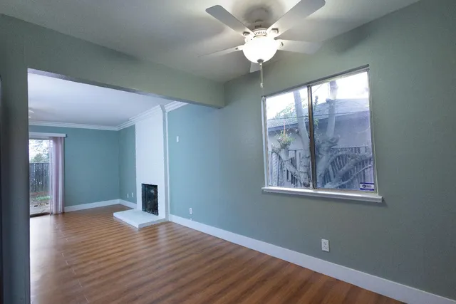 a view of an empty room with wooden floor and a window