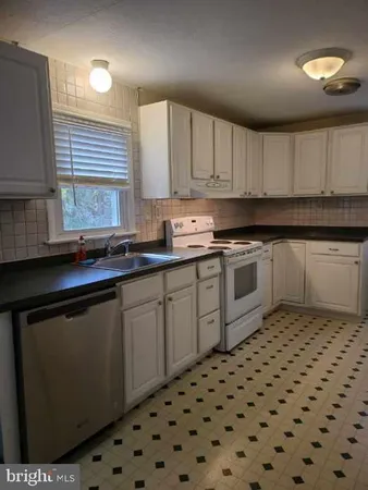 a kitchen with a sink a stove cabinets and a window