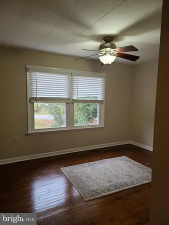 en view of an empty room with wooden floor and a window