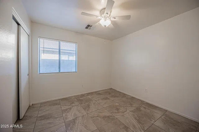 an empty room with windows and fan