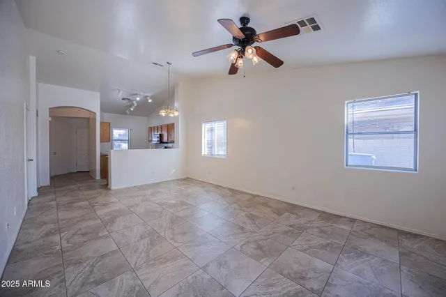a view of a livingroom with a ceiling fan a kitchen space and a window