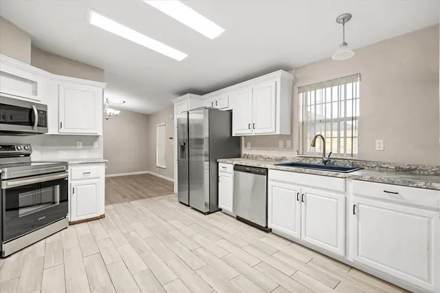 a kitchen with granite countertop a refrigerator stove top oven and sink