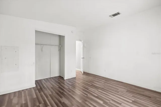a view of an empty room with wooden floor and closet