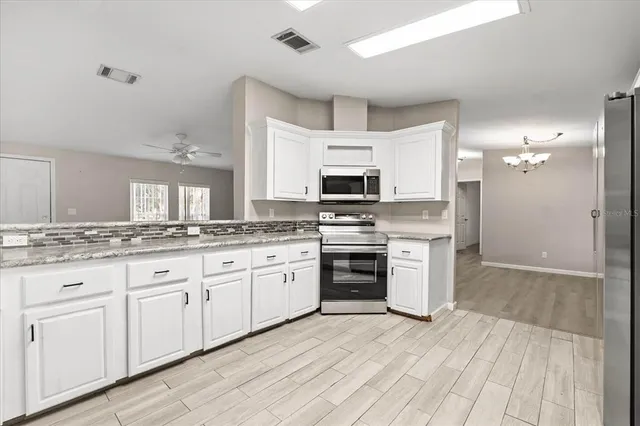 a kitchen with granite countertop white cabinets and stainless steel appliances