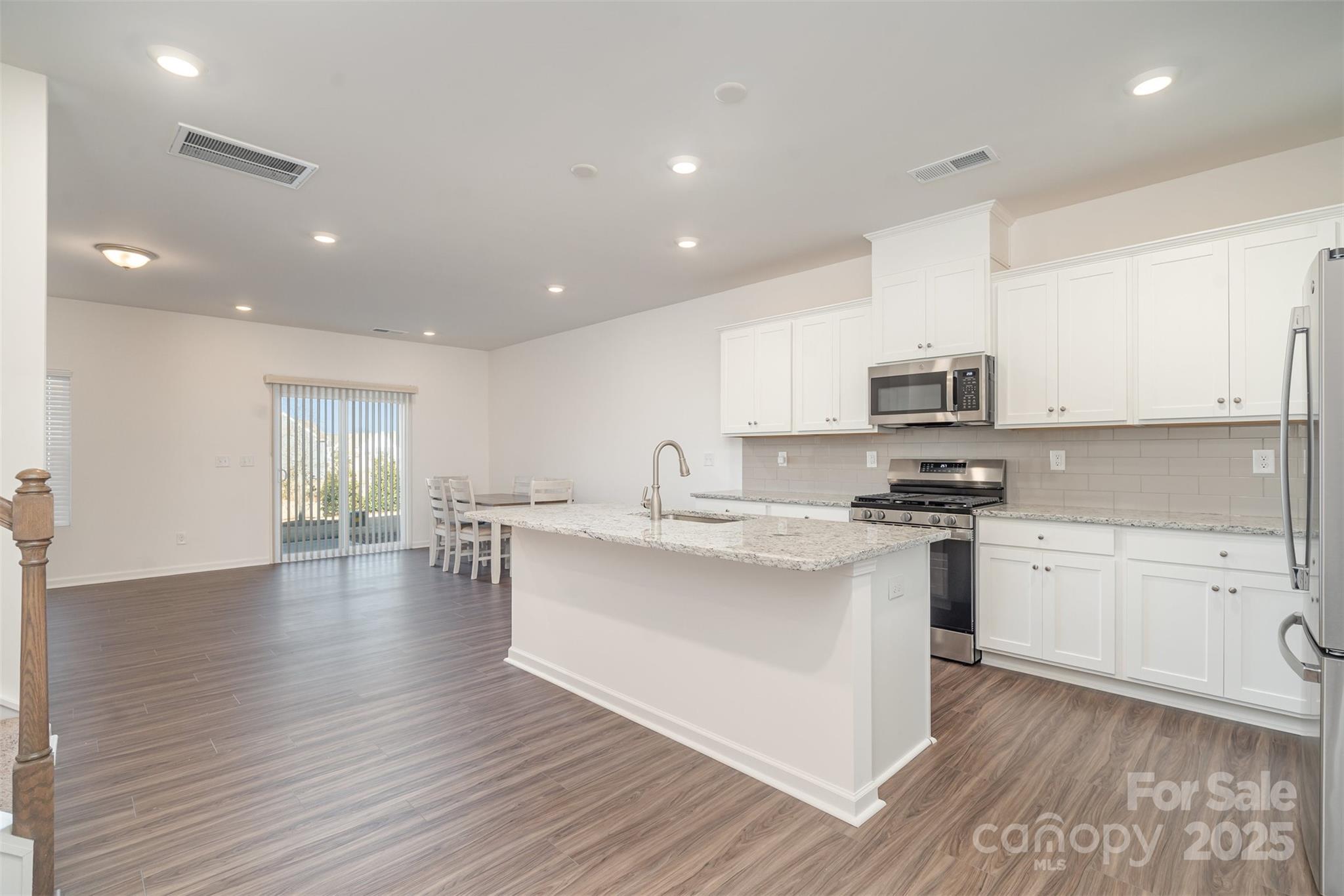 781 Earhart Street Northwest Concord, NC 28027 - Photo 16 of 31 a kitchen with stainless steel appliances a sink dishwasher a stove and white cabinets with wooden floor