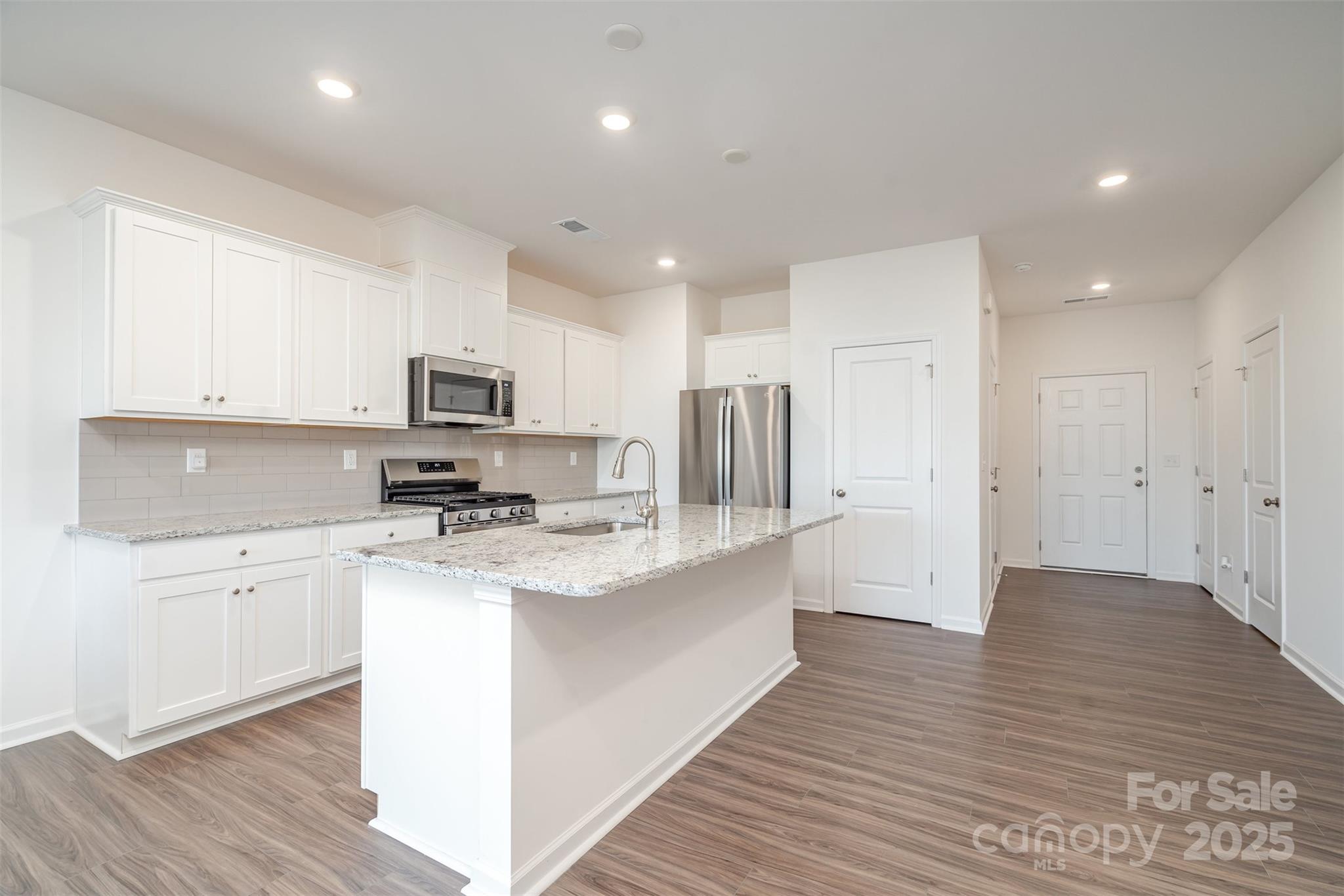 781 Earhart Street Northwest Concord, NC 28027 - Photo 3 of 31 a kitchen with stainless steel appliances a sink a stove a refrigerator cabinets and a wooden floor