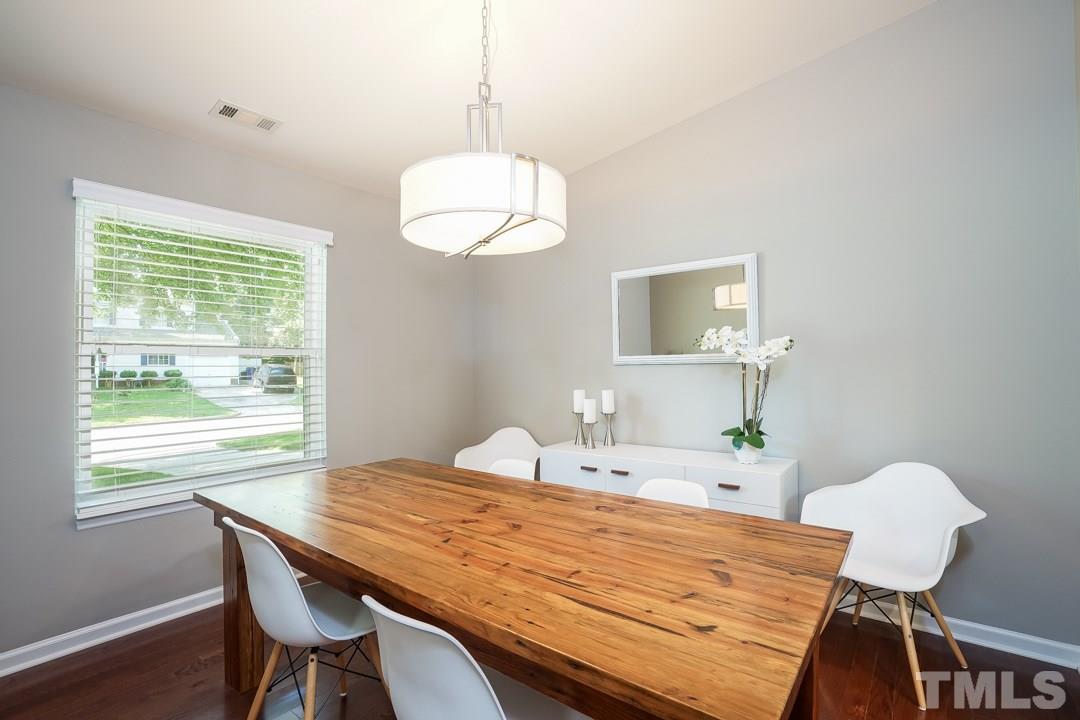 2433 Village Grove Road Raleigh, NC 27613 - Photo 3 of 24 a dining room with wooden floor a chandelier a wooden table and chairs