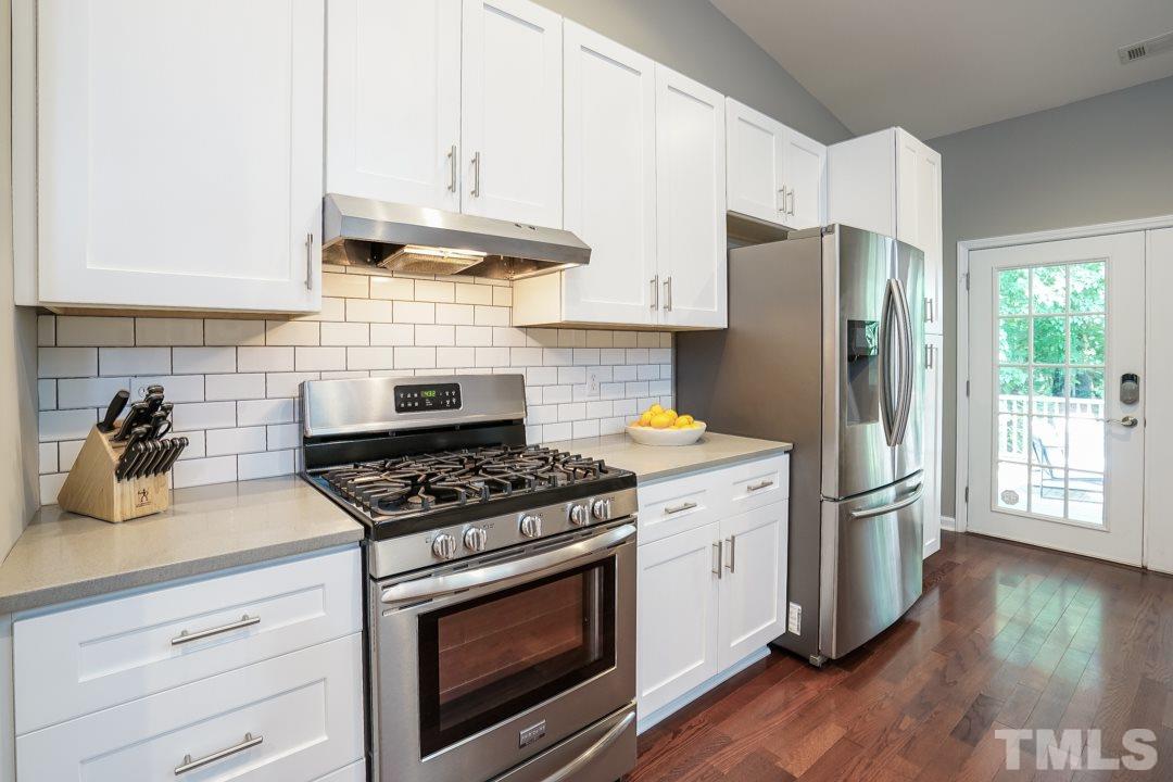 2433 Village Grove Road Raleigh, NC 27613 - Photo 5 of 24 a kitchen with stainless steel appliances wooden floor sink and wooden cabinets
