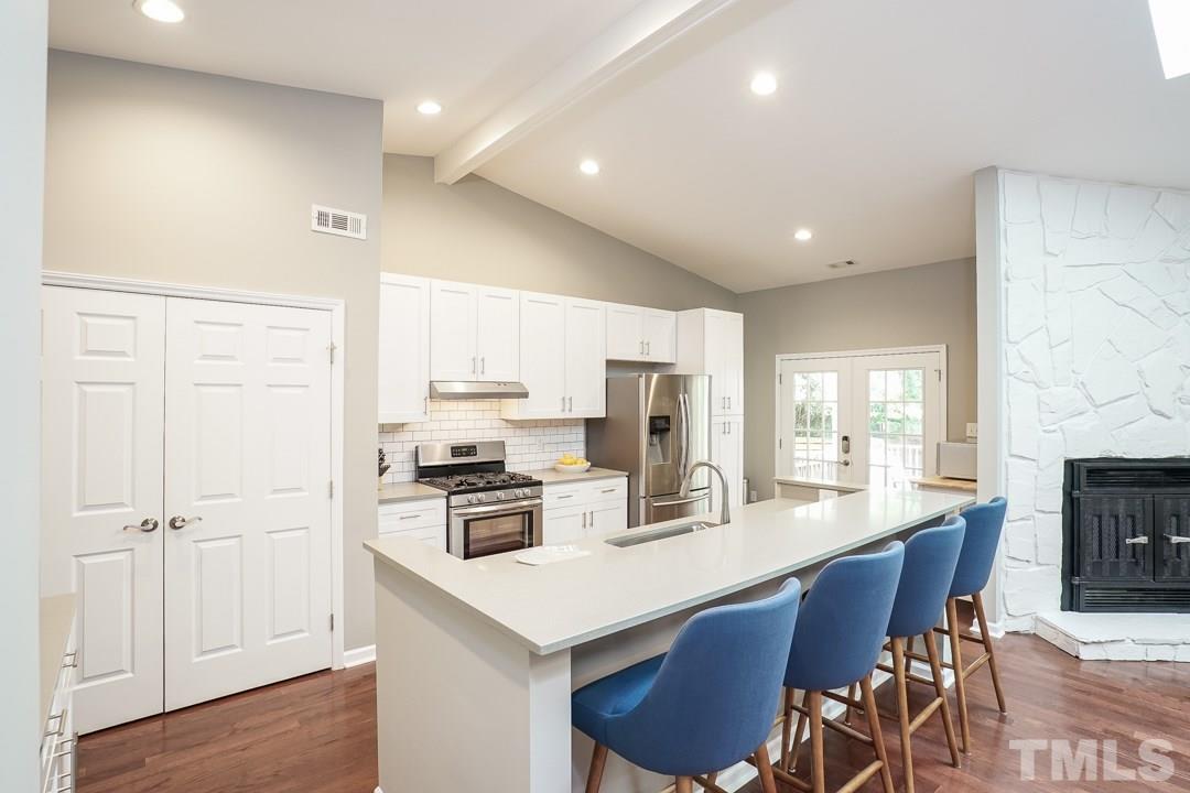 2433 Village Grove Road Raleigh, NC 27613 - Photo 8 of 24 a kitchen with stainless steel appliances granite countertop a stove a refrigerator a sink a dining table and chairs