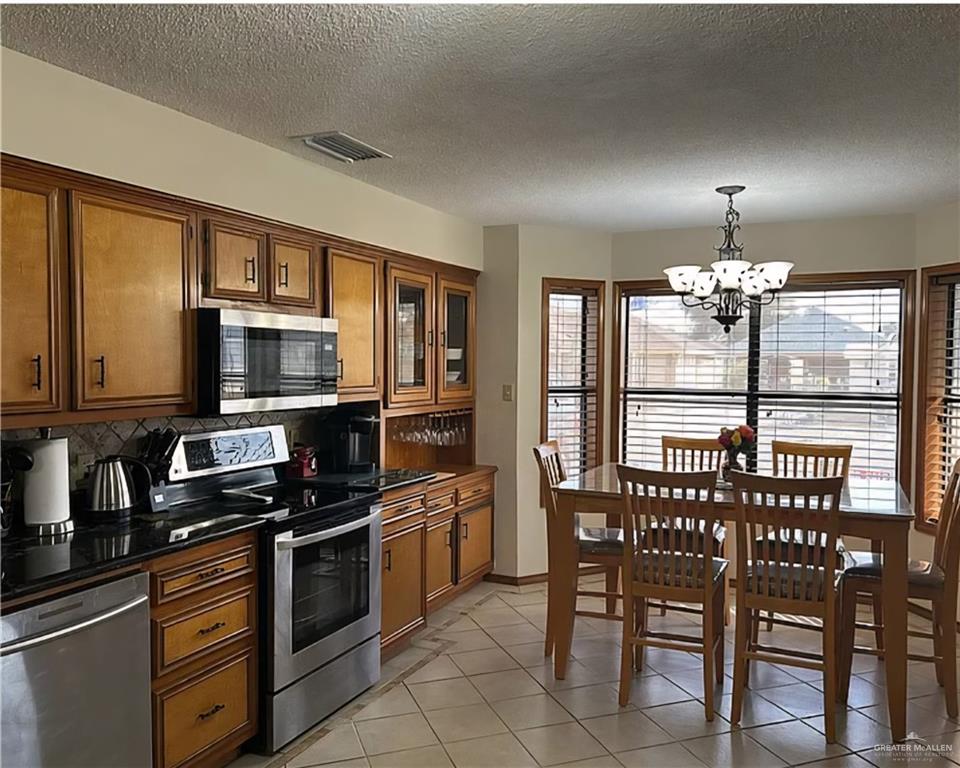 402 Jupiter Street Mission, TX 78572 - Photo 8 of 27 a kitchen with stainless steel appliances granite countertop a stove top oven a sink dishwasher a dining table and chairs with wooden floor