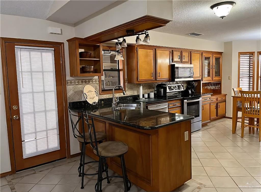 402 Jupiter Street Mission, TX 78572 - Photo 9 of 27 a kitchen with stainless steel appliances granite countertop a sink and a table
